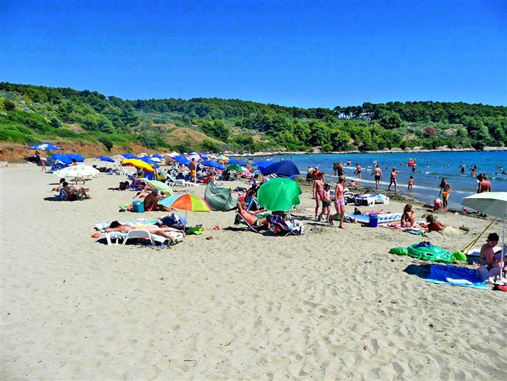 Sandy Pržina beach in Lumbarda on Korčula with shallow water and beach umbrellas